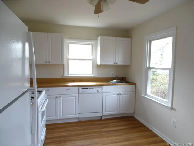 a view of a kitchen with a sink dishwasher and wooden cabinets