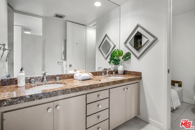 a bathroom with a granite countertop sink and a toilet