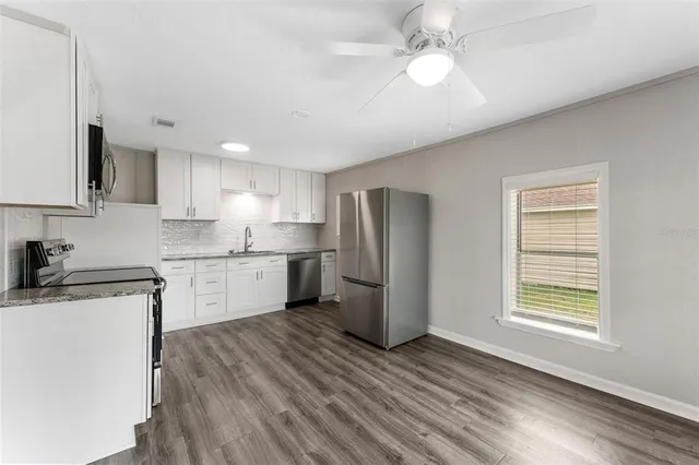 a kitchen with a refrigerator a sink and dishwasher with wooden floor
