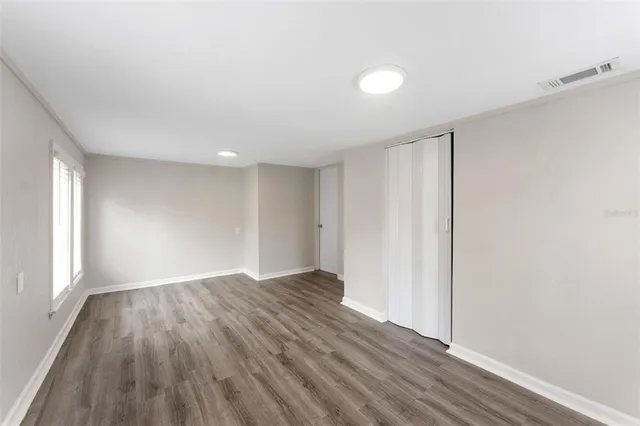 a view of an empty room with wooden floor and a window