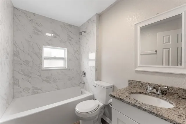 a bathroom with a granite countertop sink a toilet and a bathtub