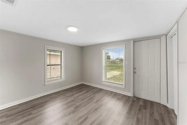 a view of an empty room with wooden floor and a window