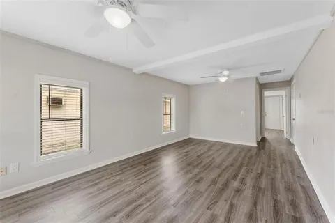 a view of an empty room with wooden floor and a window