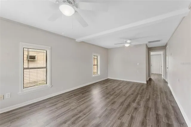 a view of an empty room with wooden floor and a window