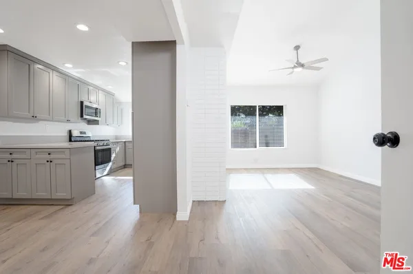 an empty room with wooden floor chandelier fan and windows