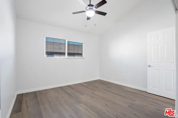 an empty room with wooden floor fan and windows