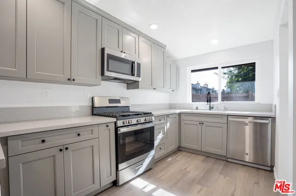 a kitchen with stainless steel appliances granite countertop a stove a sink and a microwave