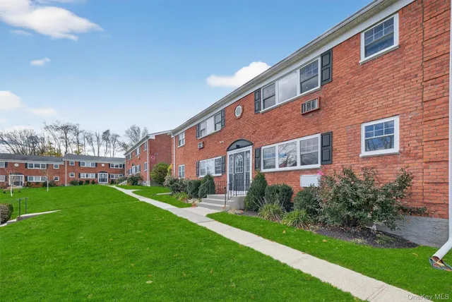 a front view of a building with garden and trees