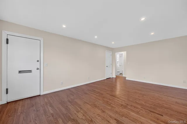 a view of an empty room with wooden floor and closet
