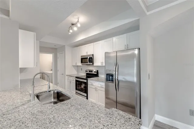 a kitchen with stainless steel appliances granite countertop a refrigerator sink and stove