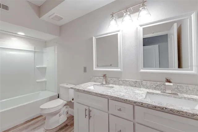 a bathroom with a granite countertop toilet sink and mirror