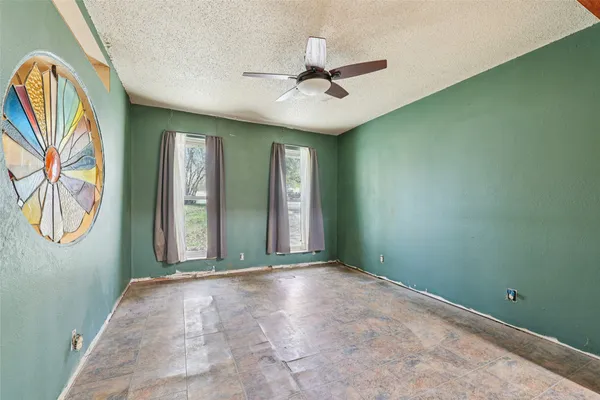 an empty room with windows and fan