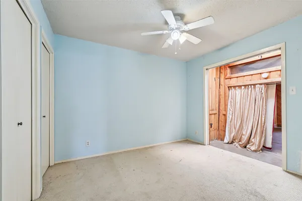 an empty room with windows and fan