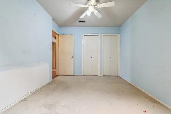 an empty room with a chandelier fan and windows