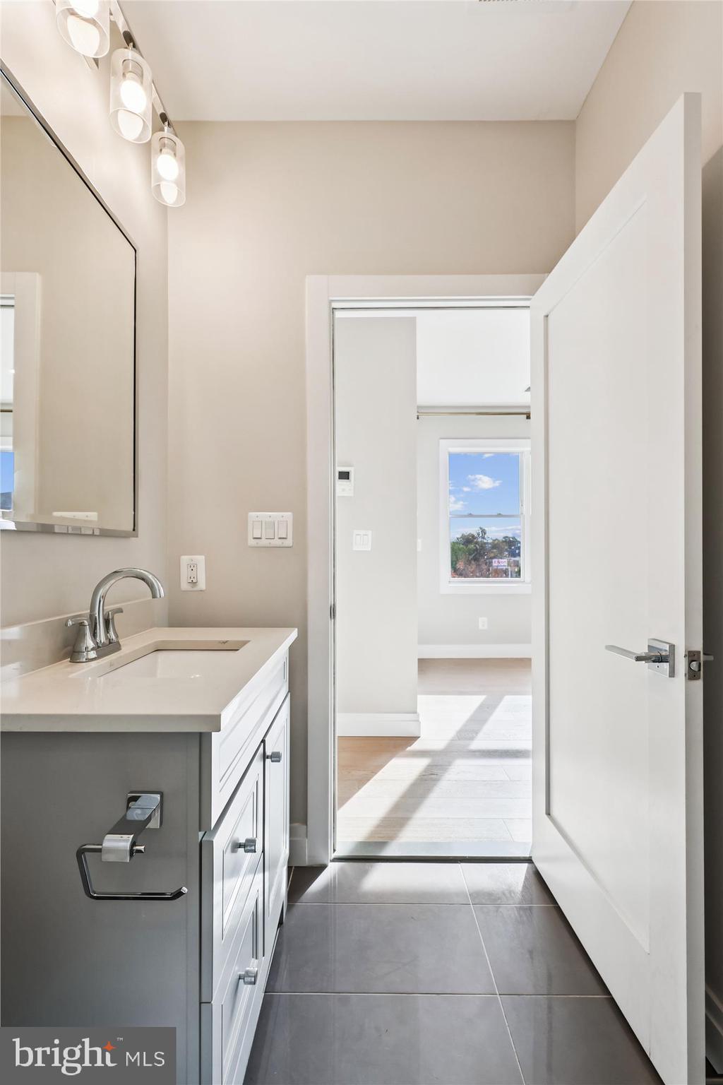 1102 Staples Street Northeast, Unit 301 Washington, DC 20002 - Photo 10 of 24 a spacious bathroom with a granite countertop sink a mirror and a bathtub