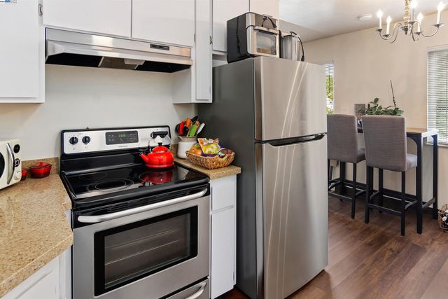 a kitchen with stainless steel appliances a refrigerator a stove and a dining table with wooden floor