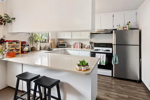 a kitchen with stainless steel appliances a white table chairs refrigerator and cabinets