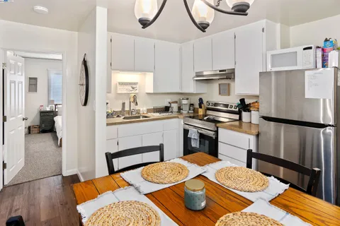 a kitchen with a refrigerator a stove a sink dishwasher and white cabinets with wooden floor