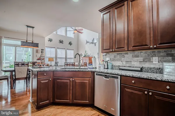 a kitchen with stainless steel appliances granite countertop a stove top oven a sink dishwasher a dining table and chairs with wooden floor