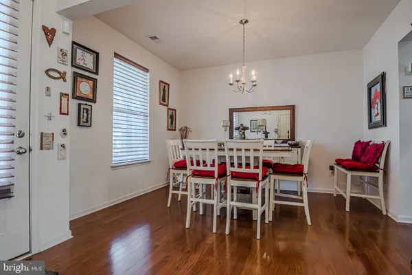 a dining room with wooden floor a chandelier a wooden table and chairs
