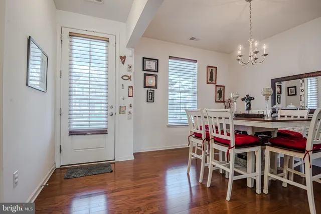 a dining room with wooden floor a chandelier a wooden table and chairs