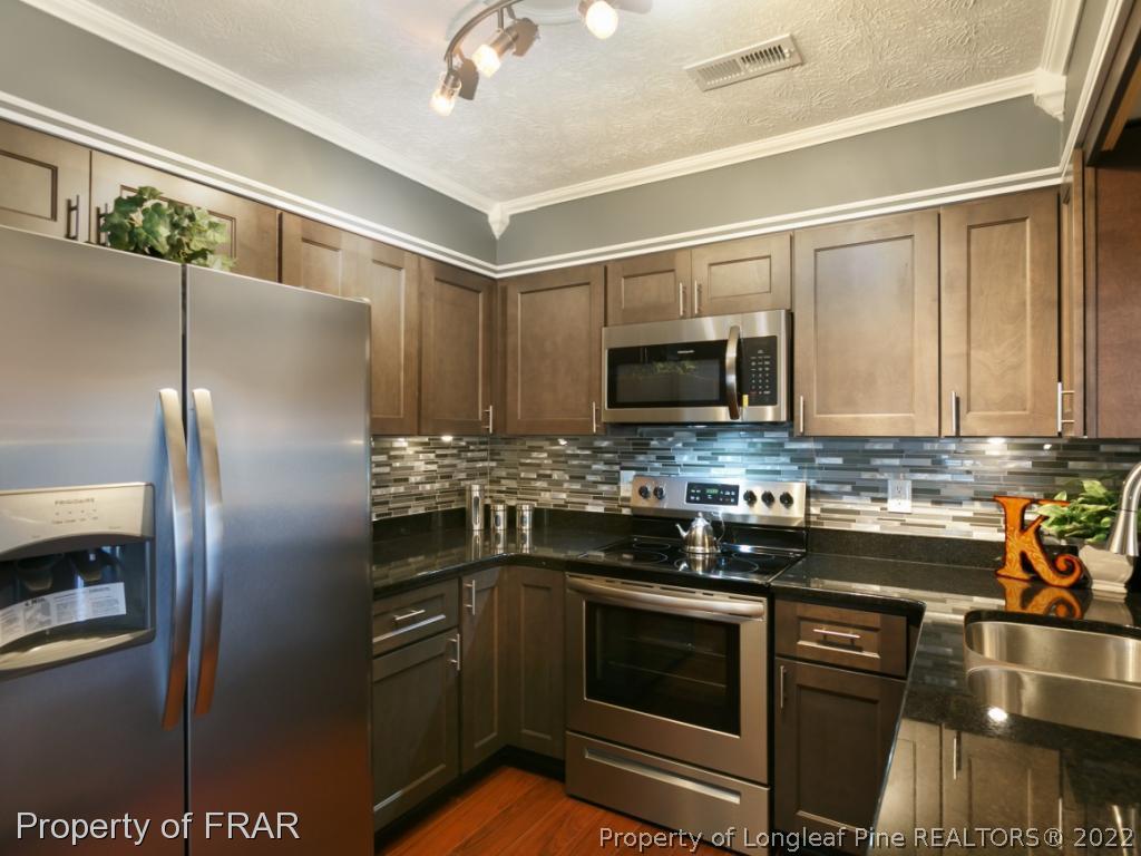 1007 Landau Road Fayetteville, NC 28311 - Photo 16 of 34 a kitchen with stainless steel appliances granite countertop a refrigerator a stove and a sink with wooden floor