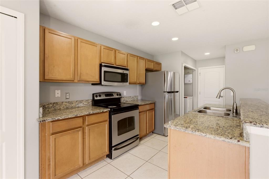 253 Bella Rosa Circle Sanford, FL 32771 - Photo 8 of 22 a kitchen with stainless steel appliances granite countertop a stove a sink and a microwave
