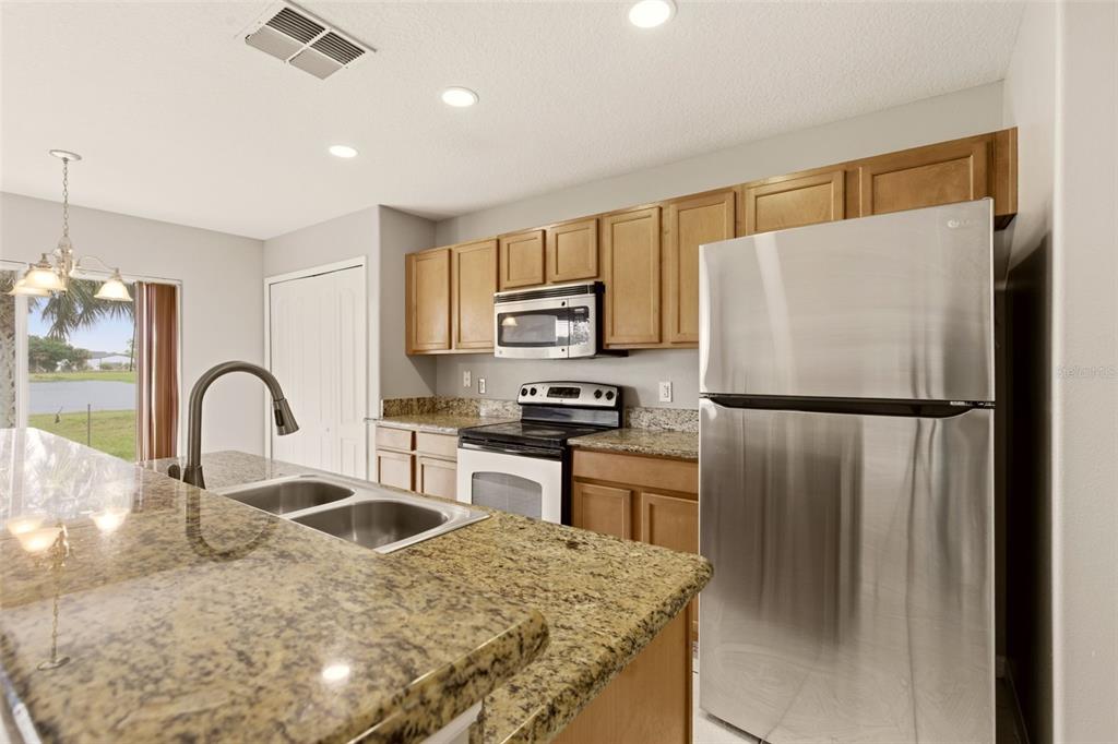 253 Bella Rosa Circle Sanford, FL 32771 - Photo 9 of 22 a kitchen with stainless steel appliances granite countertop a refrigerator a stove a sink a oven with a dining table and chairs