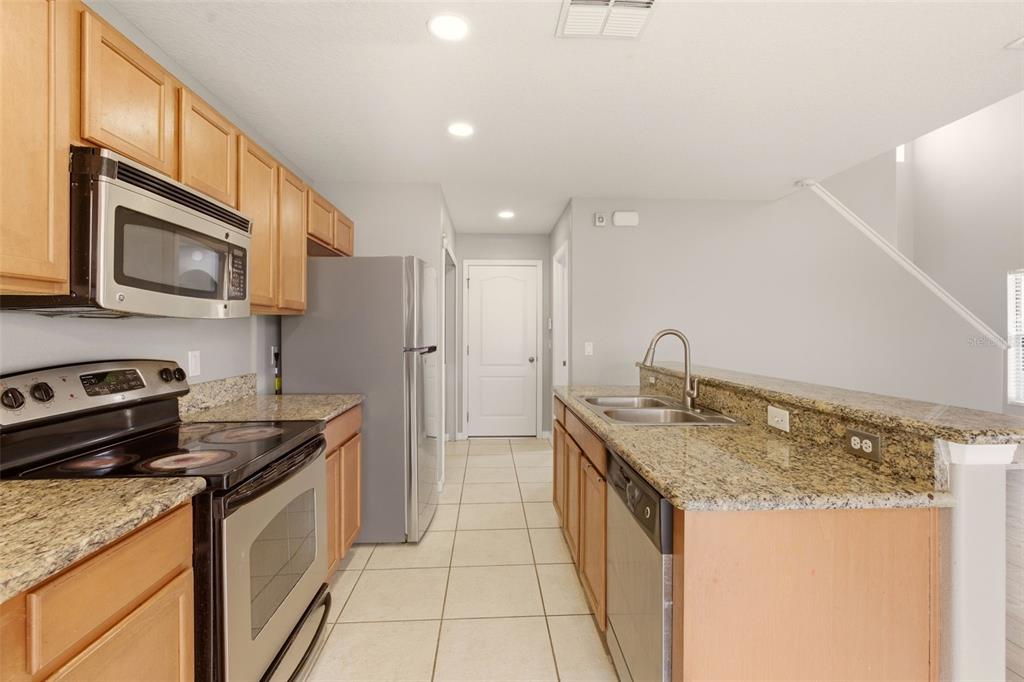 253 Bella Rosa Circle Sanford, FL 32771 - Photo 10 of 22 a kitchen with stainless steel appliances granite countertop a sink stove and refrigerator