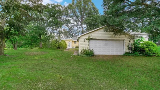 a backyard of a house with plants and large tree