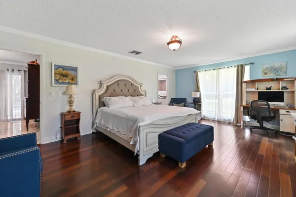 a spacious bedroom with a bed and wooden floor
