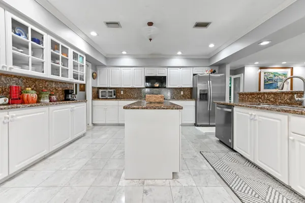 a large white kitchen with lots of counter space cabinets and appliances
