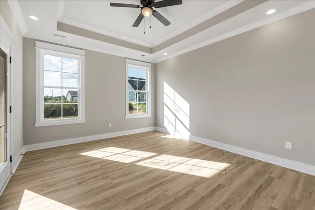 an empty room with wooden floor fan and windows
