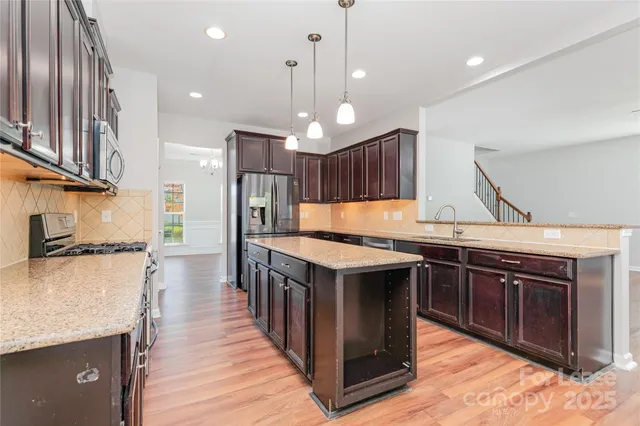 a kitchen with stainless steel appliances granite countertop a kitchen island a stove and a sink