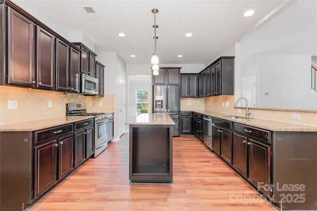 a large kitchen with stainless steel appliances wooden cabinets and a stove top oven