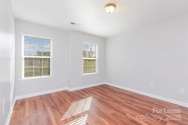 a view of a bedroom with wooden floor and window