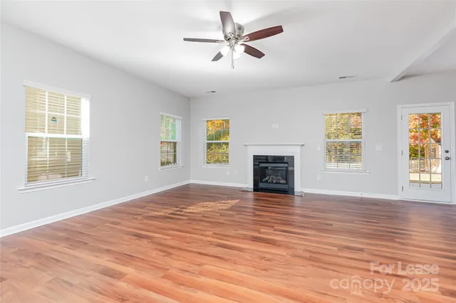 a view of an empty room with window and wooden floor