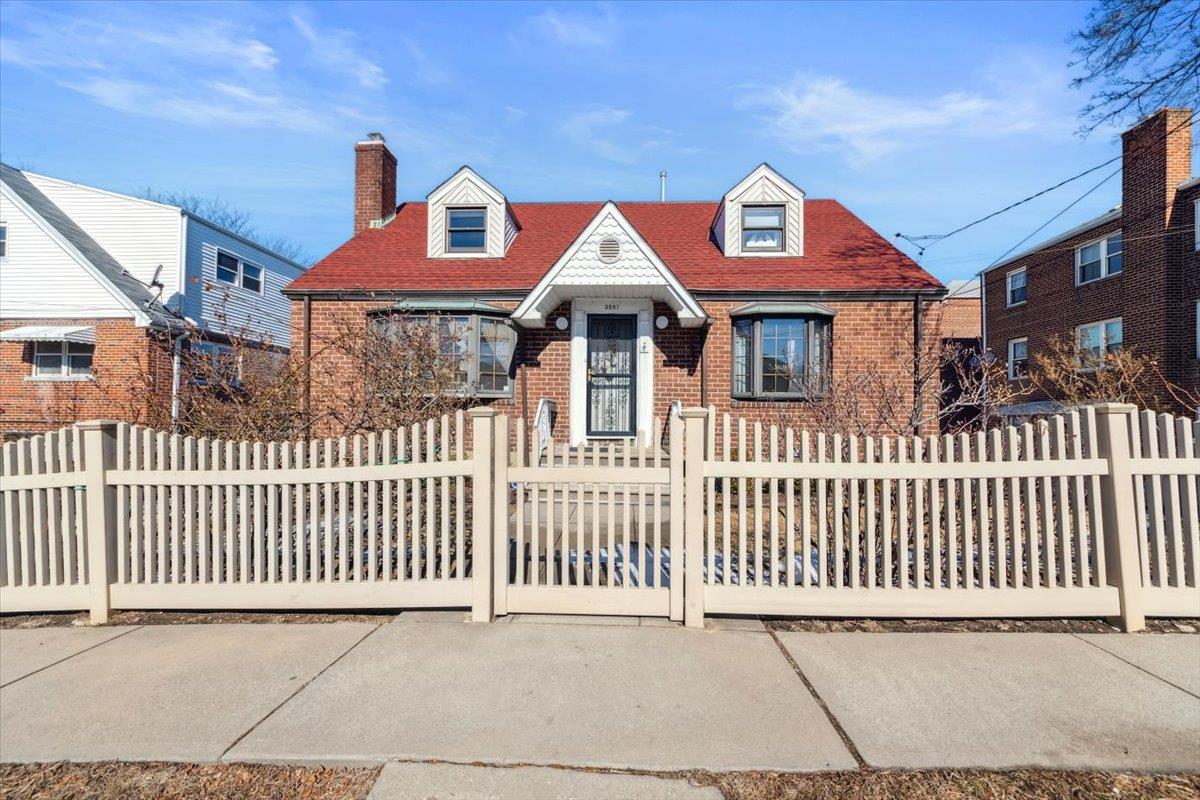 View of front of property featuring a fenced front yard, a chimney, and brick siding
