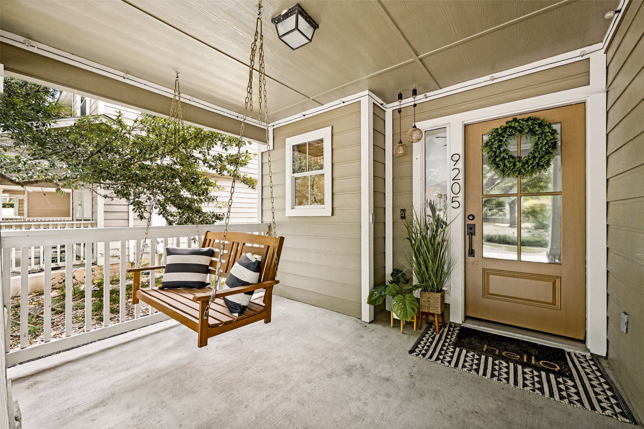 9205 Rowlands Sayle Road Austin, TX 78744 - Photo 4 of 25 A welcoming covered porch with a swinging bench offers a delightful spot for outdoor relaxation.