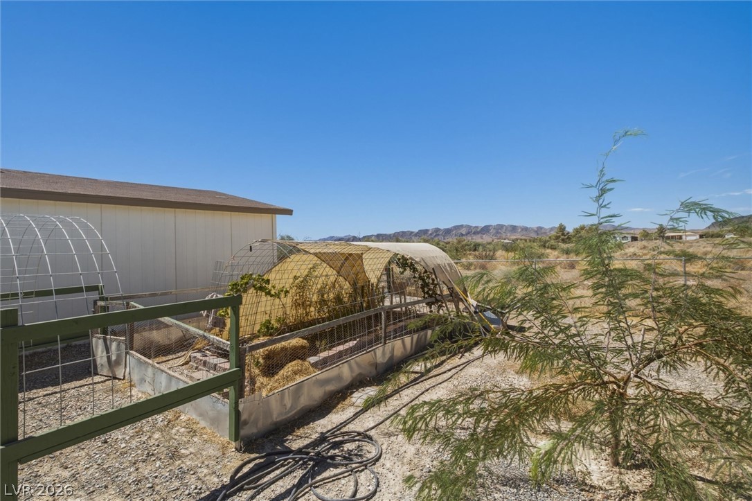 2380 West Simkins Road Pahrump, NV 89060 - Photo 32 of 38 An expansive outdoor space features structures for gardening set against a mountain backdrop.