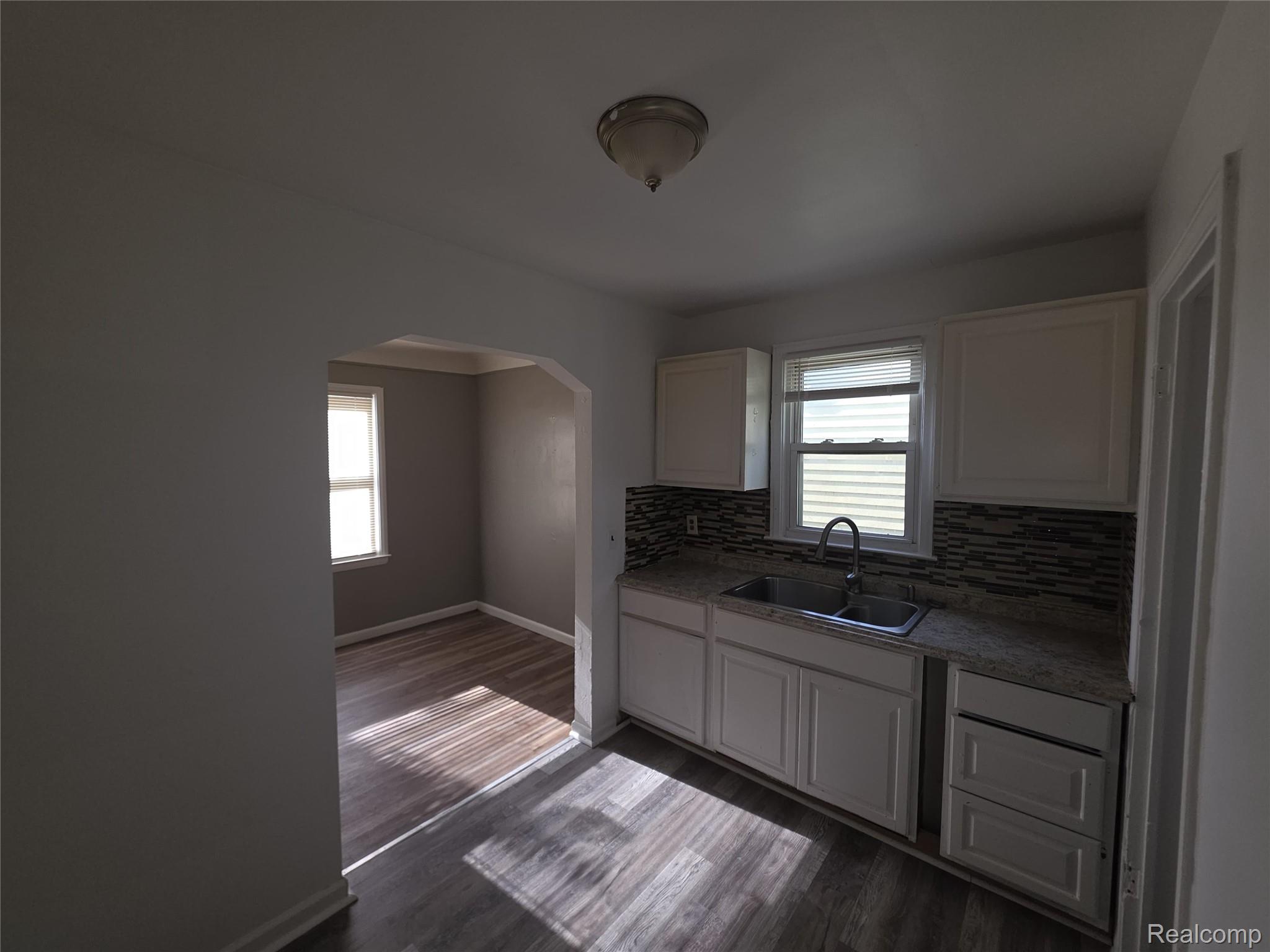 9025 Burt Road Detroit, MI 48228 - Photo 4 of 12 Kitchen featuring white cabinetry, a double basin stainless steel sink, and a granite-style countertop