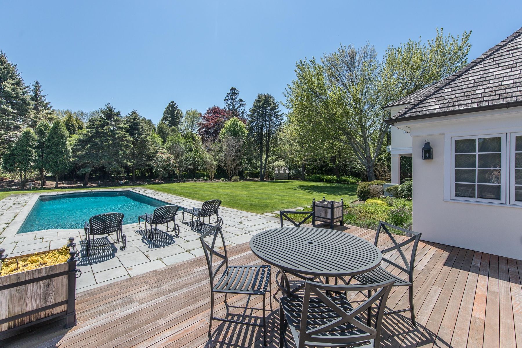 8 Pondview Lane East Hampton, NY 11937 - Photo 4 of 23 a view of a roof deck with table and chairs under an umbrella with wooden floor