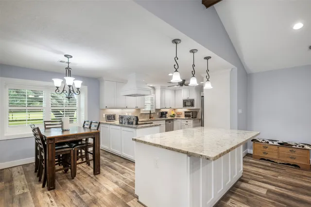 a kitchen with kitchen island a dining table and chairs