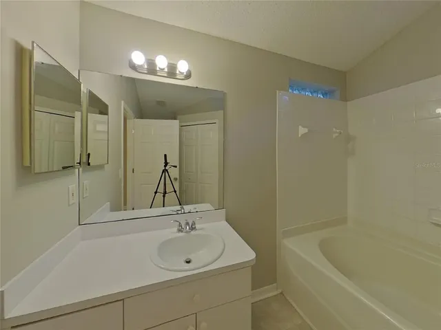 a bathroom with a sink a large mirror and a bathtub
