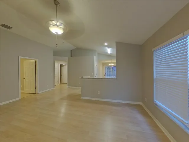 en empty room with windows and chandelier fan