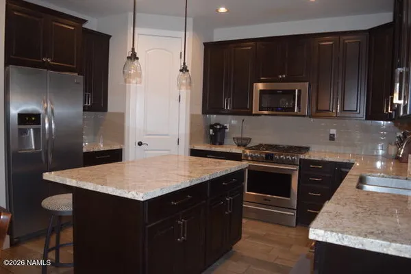 a kitchen with stainless steel appliances granite countertop a stove refrigerator and microwave