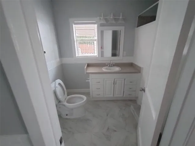 a bathroom with a sink a toilet and a window