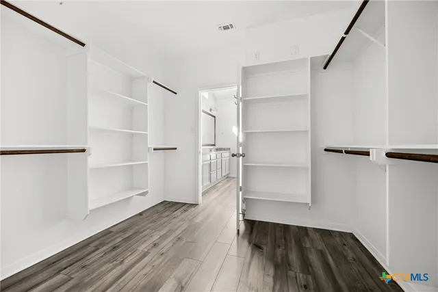 a view of walk in closet with wooden floor