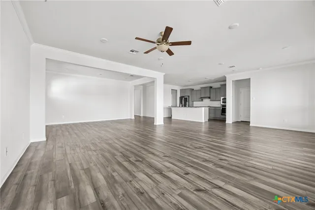 a view of empty room with wooden floor and ceiling fan