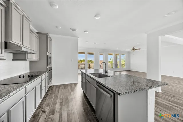 a kitchen with granite countertop stainless steel appliances a sink stove top oven and cabinets